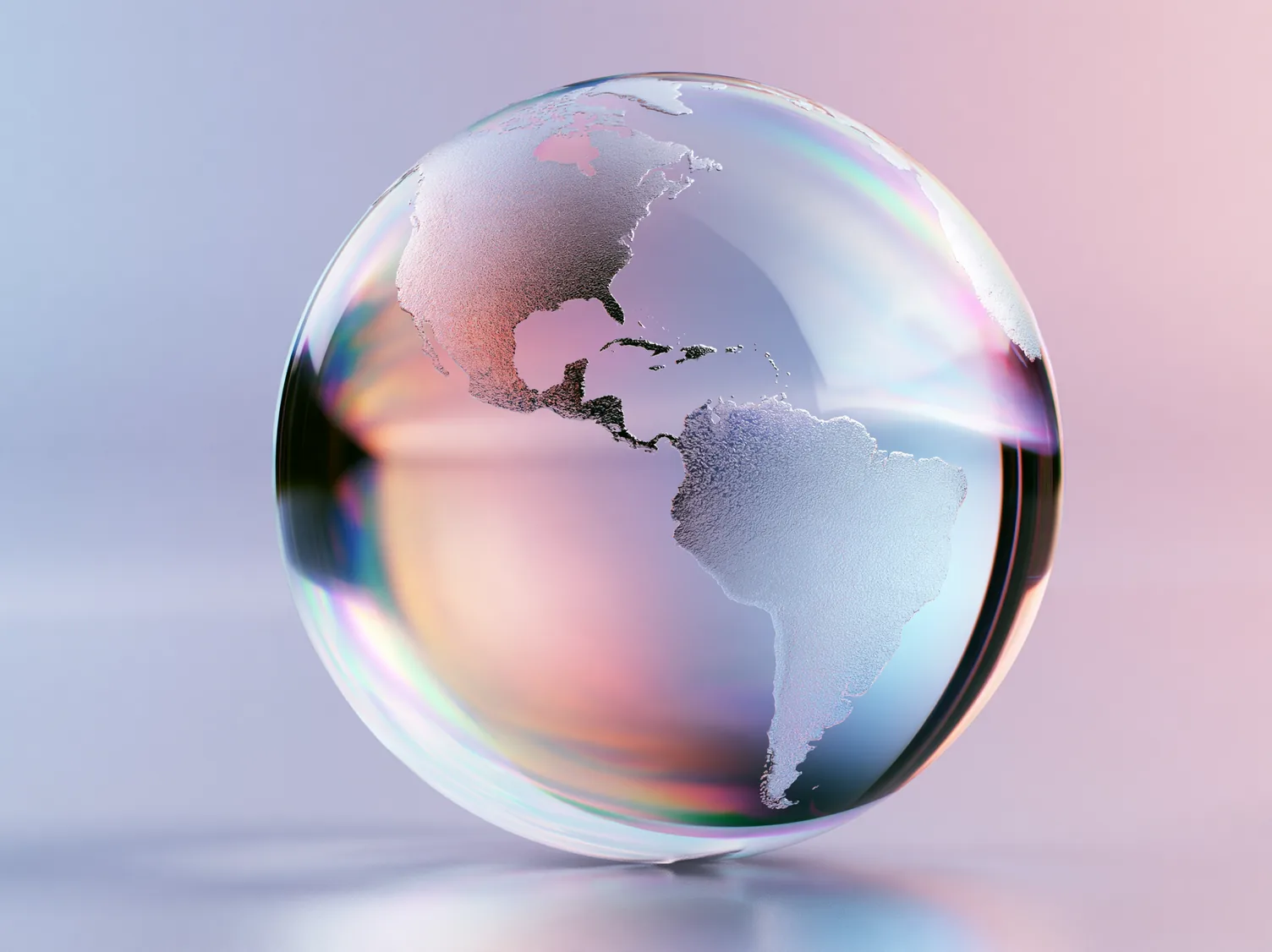 A frosted glass globe turned to face the Americas, the continents rendered in a rough crystalline texture against clear glass, with a band of rainbow refraction curving through it and a soft pink and lilac backdrop behind.